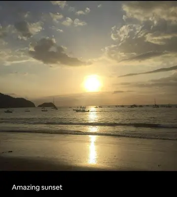 a sunset on the beach with boats in the water at Renovated apartment in Las Palmas in Coco