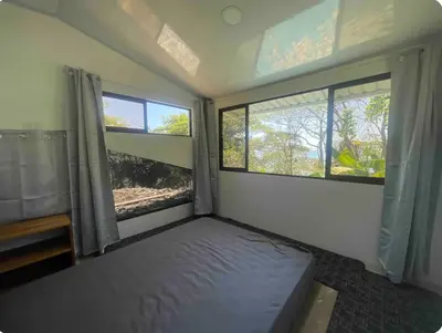 a bedroom with two windows and a bed in it at Beachfront tiny bungalow in Cóbano