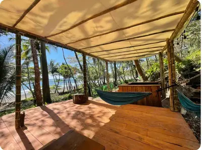 a hammock on a deck with a view of the ocean at Beachfront tiny bungalow in Cóbano