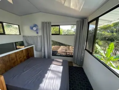 a bedroom with a bed and two windows at Beachfront tiny bungalow in Cóbano