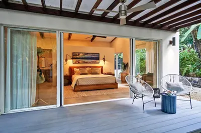 a master bedroom with a bed and sliding glass doors at CasaMAR Santa Teresa on the Beach in Carmen