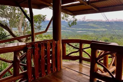 a wooden porch with a view of the mountains at Cabaña Vistas Paraíso in Turrialba
