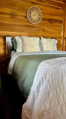 a bedroom with a bed with a clock on the wall at Cabaña Vistas Paraíso in Turrialba