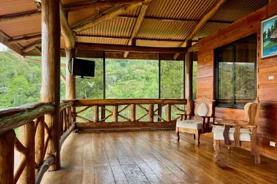 a room with a balcony with a television and chairs at Cabaña Vistas Paraíso in Turrialba