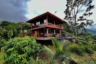 a large wooden house on a hill with trees at Cabaña Vistas Paraíso in Turrialba