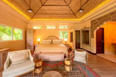 a bedroom with a bed and a couch and chairs at Jazz Studio in Nosara
