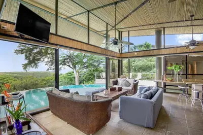 a living room with a couch and a tv and a pool at Villa La Loma, Oceanview, Private Pool and AC! in Tarcoles