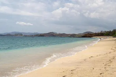 a beach with people walking on the sand and the water at Mercado 26- Ocean View Condo At Las Catalinas in Playa Danta