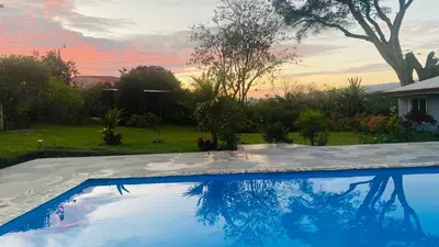 a swimming pool in a yard with a sunset at Casa Marigold -Apartamento Bondad in Alajuela City