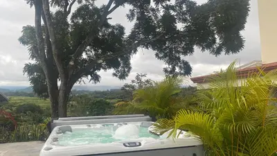 a hot tub in a garden with a tree at Casa Marigold -Apartamento Bondad in Alajuela City