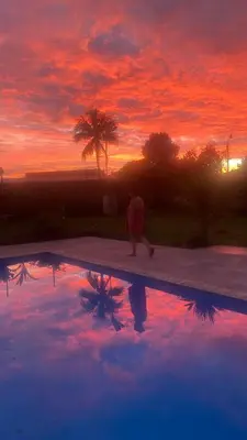 a person standing next to a swimming pool at sunset at Casa Marigold -Apartamento Bondad in Alajuela City