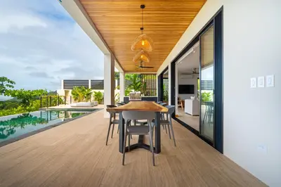 a dining room with a table and a view of a pool at Villa del Cielo - by Pura Villas in Uvita