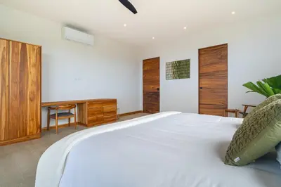 a bedroom with a white bed and a tv at Villa del Cielo - by Pura Villas in Uvita