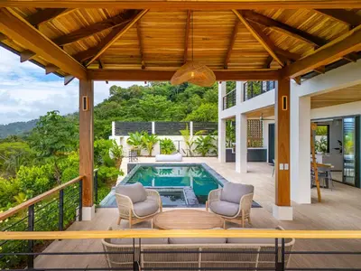 an outdoor deck with a pool and chairs and a house at Villa del Cielo - by Pura Villas in Uvita