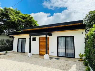 a small white house with a black roof at Casa Paloma in Playa Grande