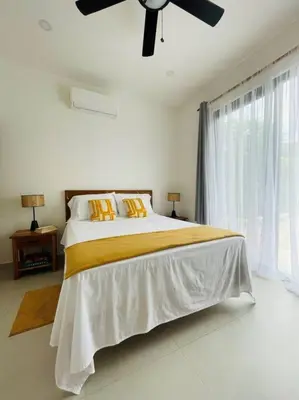 a bedroom with a bed with a ceiling fan at Casa Paloma in Playa Grande