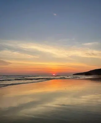a sunset on a beach with the ocean at Casa Paloma in Playa Grande