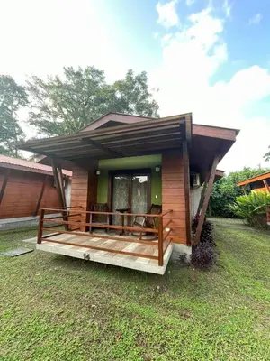 a small house with a deck in the yard at Hotel Brisas del Rio Guápiles in Jiménez