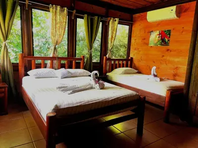 two beds sitting in a room with windows at Hotel Canto de Ballenas in Uvita