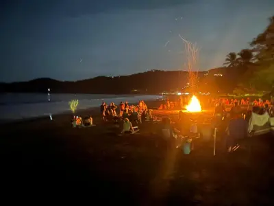 a group of people sitting around a fire on a beach at Sweet Torres Estudio 2pers in Coco