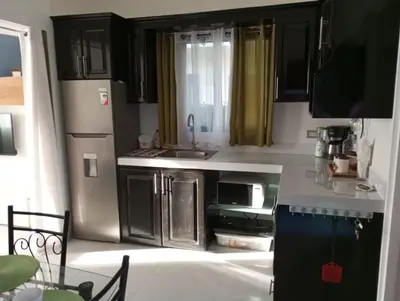 a kitchen with black cabinets and a stainless steel refrigerator at Sweet Torres Estudio 2pers in Coco