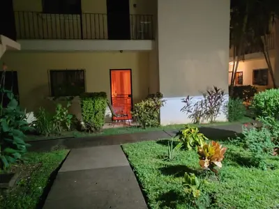 a garden in front of a building with a red door at Sweet Torres Estudio 2pers in Coco