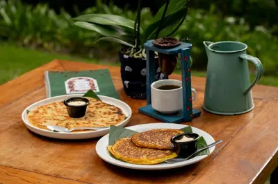 a wooden table with two plates of pancakes and coffee at Hotel Boutique Casona del Cafetal and Lakeside Restaurant in Cachí