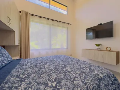 a bedroom with a bed and a tv and a window at Coco Luna House 2 bed 3 bath in Coco