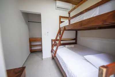 a bedroom with two bunk beds with white sheets at SeaSurf House in Esterillos