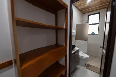 a small bathroom with a toilet and a wooden door at SeaSurf House in Esterillos