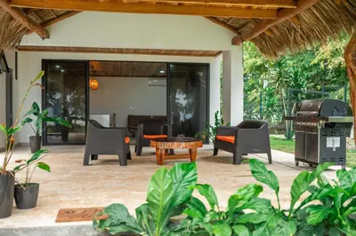 an outdoor patio with chairs and a grill at SeaSurf House in Esterillos