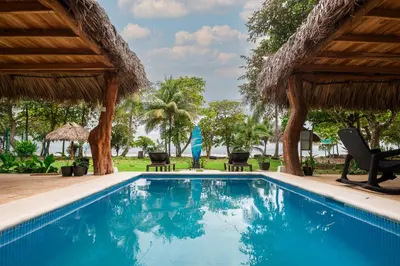 a pool at a resort with chairs and umbrellas at SeaSurf House in Esterillos