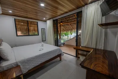 a bedroom with a bed and a table and a window at SeaSurf House in Esterillos