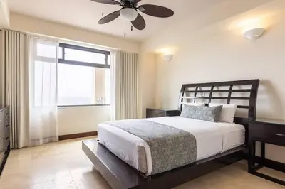 a bedroom with a bed with a ceiling fan and a window at 3 Bedroom Condo in Croc's Casino Resort in Jacó