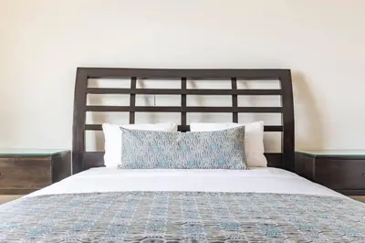 a bed with a wooden headboard and a blue pillow at 3 Bedroom Condo in Croc's Casino Resort in Jacó