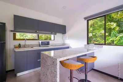a kitchen with blue cabinets and a counter with stools at Casa para Vacacionar Increible en Bejuco in Loma