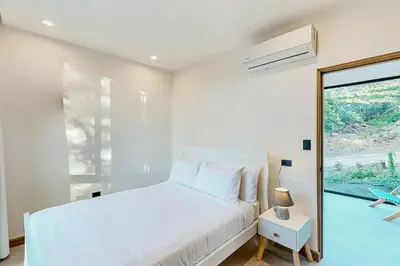 a bedroom with a white bed and a large window at Playa Conchal and Minas' Hidden Gem in Puerto Viejo
