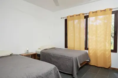 a bedroom with two beds and a window at Green Turtle Townhome #2 Private Pool & Garden 300 Mtrs to Beach in Tamarindo