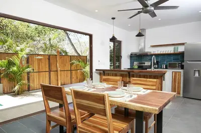 a kitchen and dining room with a wooden table and chairs at Green Turtle Townhome #2 Private Pool & Garden 300 Mtrs to Beach in Tamarindo