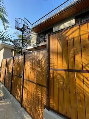 a fence in front of a building with the sun shining on it at Green Turtle Townhome #2 Private Pool & Garden 300 Mtrs to Beach in Tamarindo