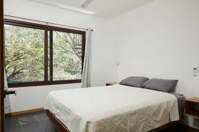 a bedroom with a bed and a large window at Green Turtle Townhome #2 Private Pool & Garden 300 Mtrs to Beach in Tamarindo