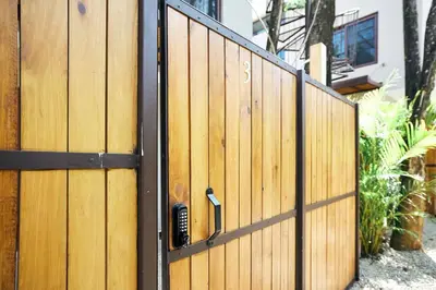 a wooden fence with a door in front of a house at Green Turtle Townhome #3 Private Pool & Garden 300 Mt to Beach in Tamarindo