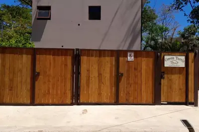 a fence with two wooden gates in front of a house at Green Turtle Townhome #3 Private Pool & Garden 300 Mt to Beach in Tamarindo