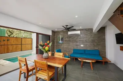a dining room with a table and a blue couch at Green Turtle Townhome #3 Private Pool & Garden 300 Mt to Beach in Tamarindo