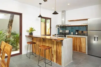 a kitchen with a counter with stools in it at Green Turtle Townhome #4 Private Pool & Garden 300Mtrs to Beach in Tamarindo