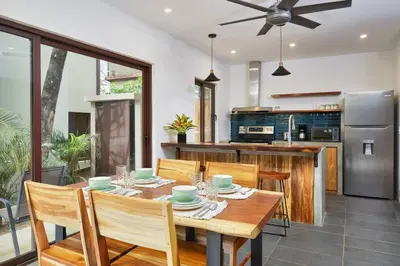 a dining room with a table and a kitchen at Green Turtle Townhome #4 Private Pool & Garden 300Mtrs to Beach in Tamarindo