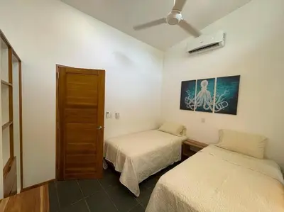 a room with two beds and a ceiling fan at Green Turtle Townhome #4 Private Pool & Garden 300Mtrs to Beach in Tamarindo