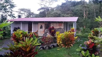 a small house with a purple roof in a garden at Nacientes Lodge in Bijagua