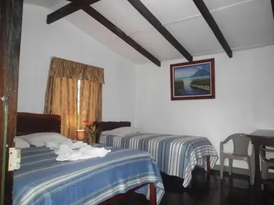 a room with two beds and a table with a desk at Nacientes Lodge in Bijagua