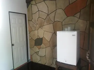a room with a wall with a stone wall at Nacientes Lodge in Bijagua